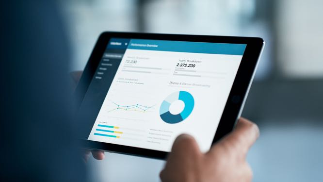 close up of a hand holding a tablet displaying charts and data